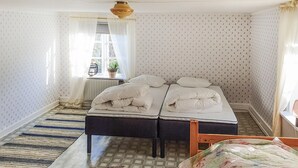 A room with two beds, a radiator, a window with curtains, a plant, and a patterned rug. - Stunning home in Södra Vi with kitchen (Södra Vi)