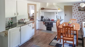 A compact kitchen with white cabinets, a wooden dining table, and a stove. - Stunning home in Södra Vi with kitchen (Södra Vi)