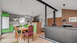 A modern kitchen with green cabinets, a dining area with a wooden table and chairs, and a grey sofa in a living area. - Beautiful home in Herning with WiFi (Herning)