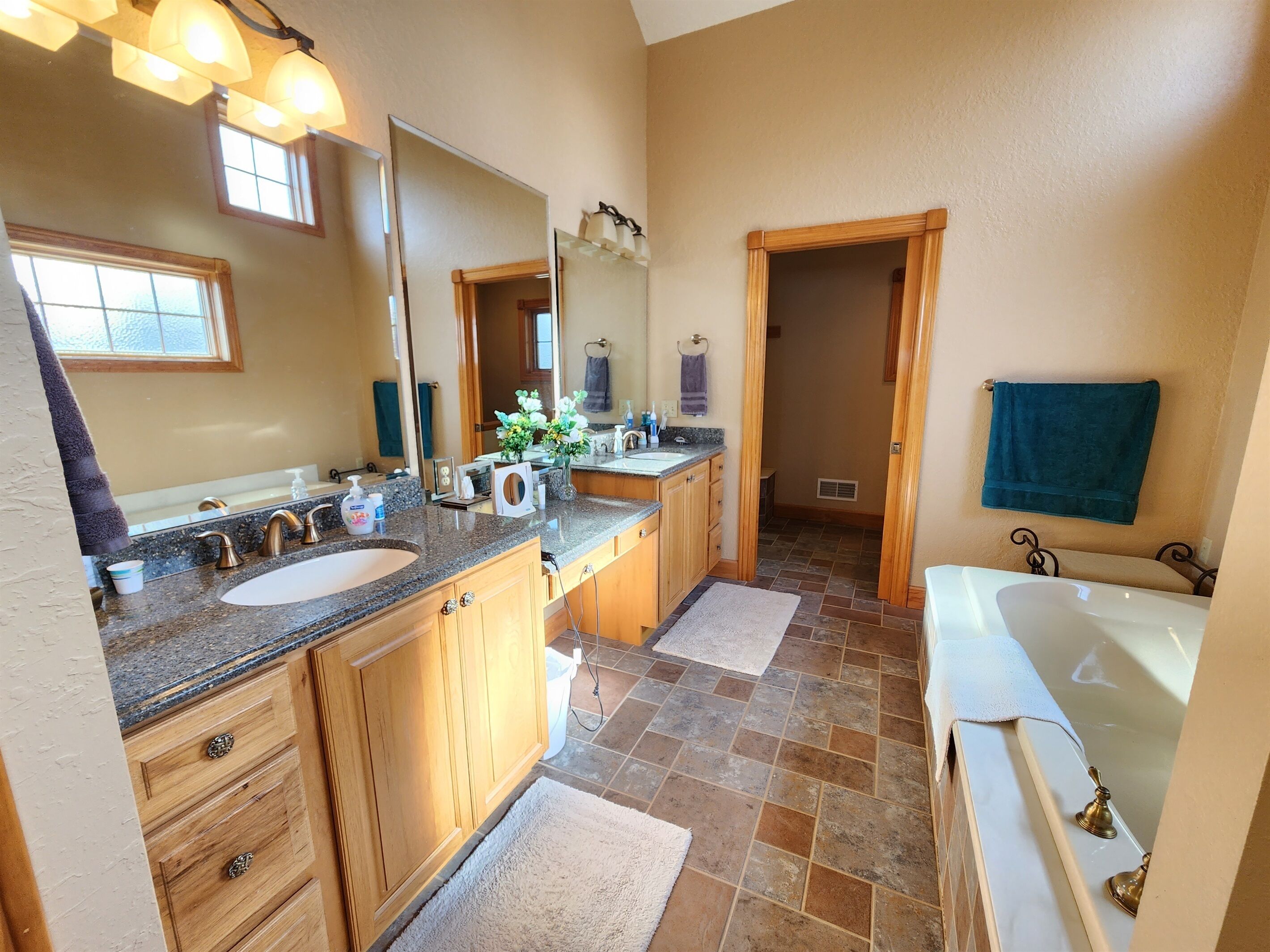 A bathroom with two sinks, a large mirror, a bathtub, and a shower area.