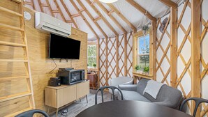 A cozy room with a wooden ceiling, a flat-screen TV, a small kitchenette, and a comfortable seating area. - Luxury Glamping Yurt with Loft, Wood-Fired Hot Tub (Sears)
