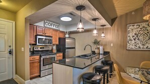 A modern kitchen with stainless steel appliances, a central island with bar stools, and pendant lighting. - Branson Condo w/ Pool & Golf Course Views! (Branson)