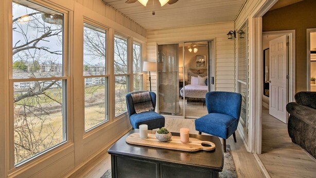 A cozy room with a ceiling fan, large windows, a wooden coffee table with candles, and a view of the outdoors. - Branson Condo w/ Pool & Golf Course Views! (Branson)