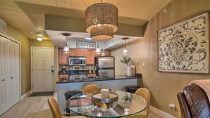 A modern kitchen with a glass dining table, a coffee station, and a large decorative wall piece. - Branson Condo w/ Pool & Golf Course Views! (Branson)