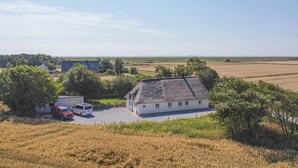Una casa di campagna con tetto di paglia, immersa tra campi e alberi.