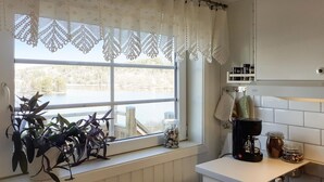 Una cocina con ventana que da a un lago, una cafetera y un tarro de especias sobre la encimera.