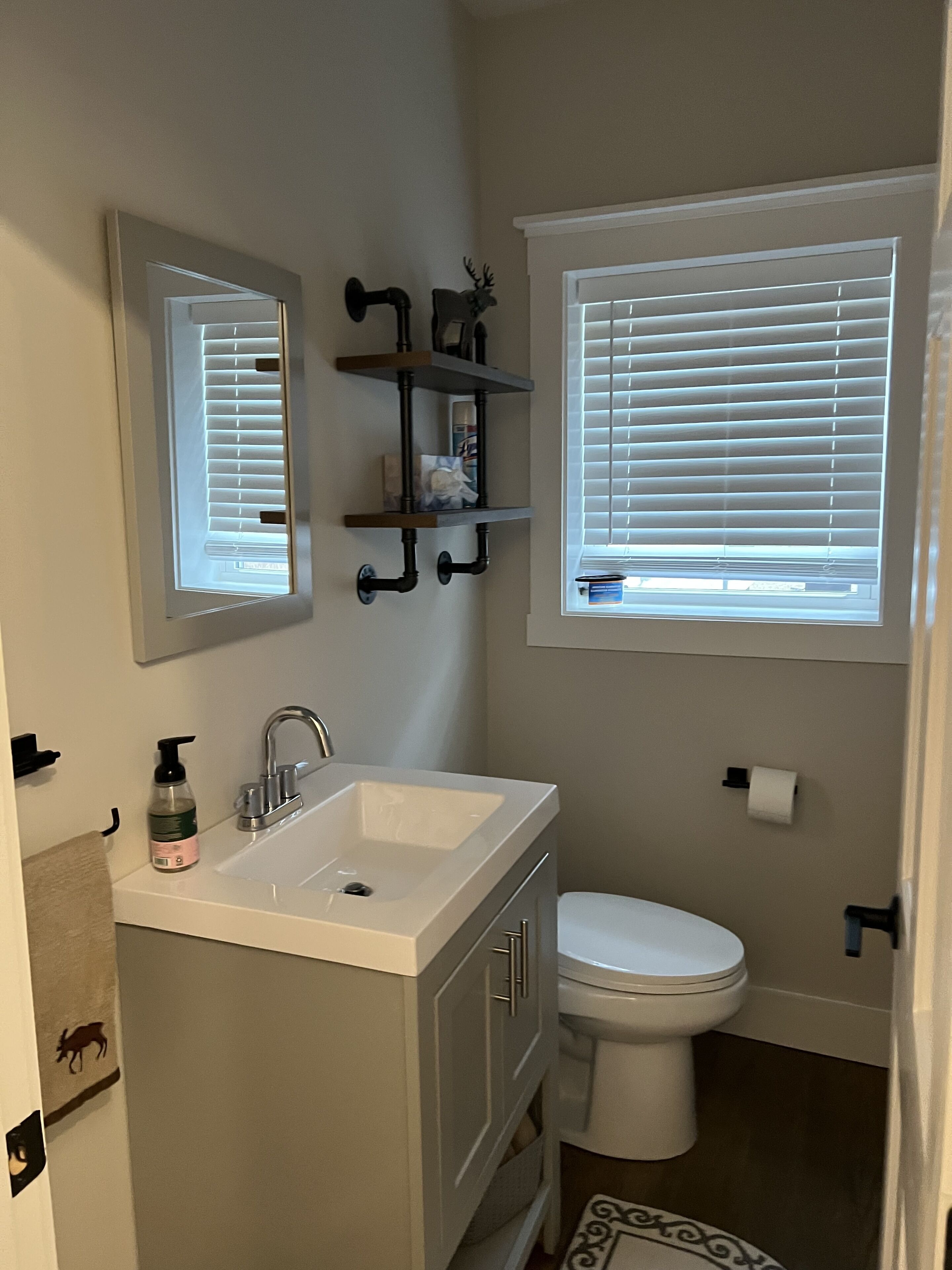 A bathroom with a white sink, a toilet, and a window with blinds.