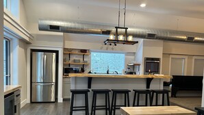 Una cocina moderna con electrodomésticos de acero inoxidable, una isla central con taburetes y un amplio ventanal.