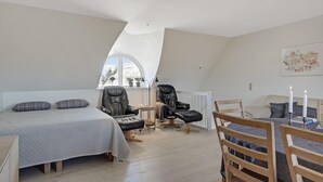 A loft bedroom with a bed, two leather chairs, a wooden dining table, and a view of the outdoors. - Stunning home in ålbæk with WiFi (Ålbæk)