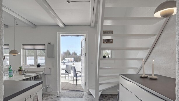 A modern kitchen with a built-in oven, a dining area with a table and chairs, and a view of the outside. - Stunning home in ålbæk with WiFi (Ålbæk)