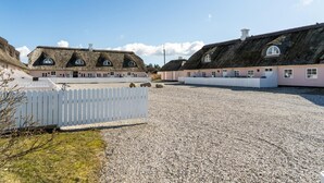 A row of thatched-roof cottages with white picket fences, gravel ground, and a clear sky. - Stunning home in ålbæk with WiFi (Ålbæk)