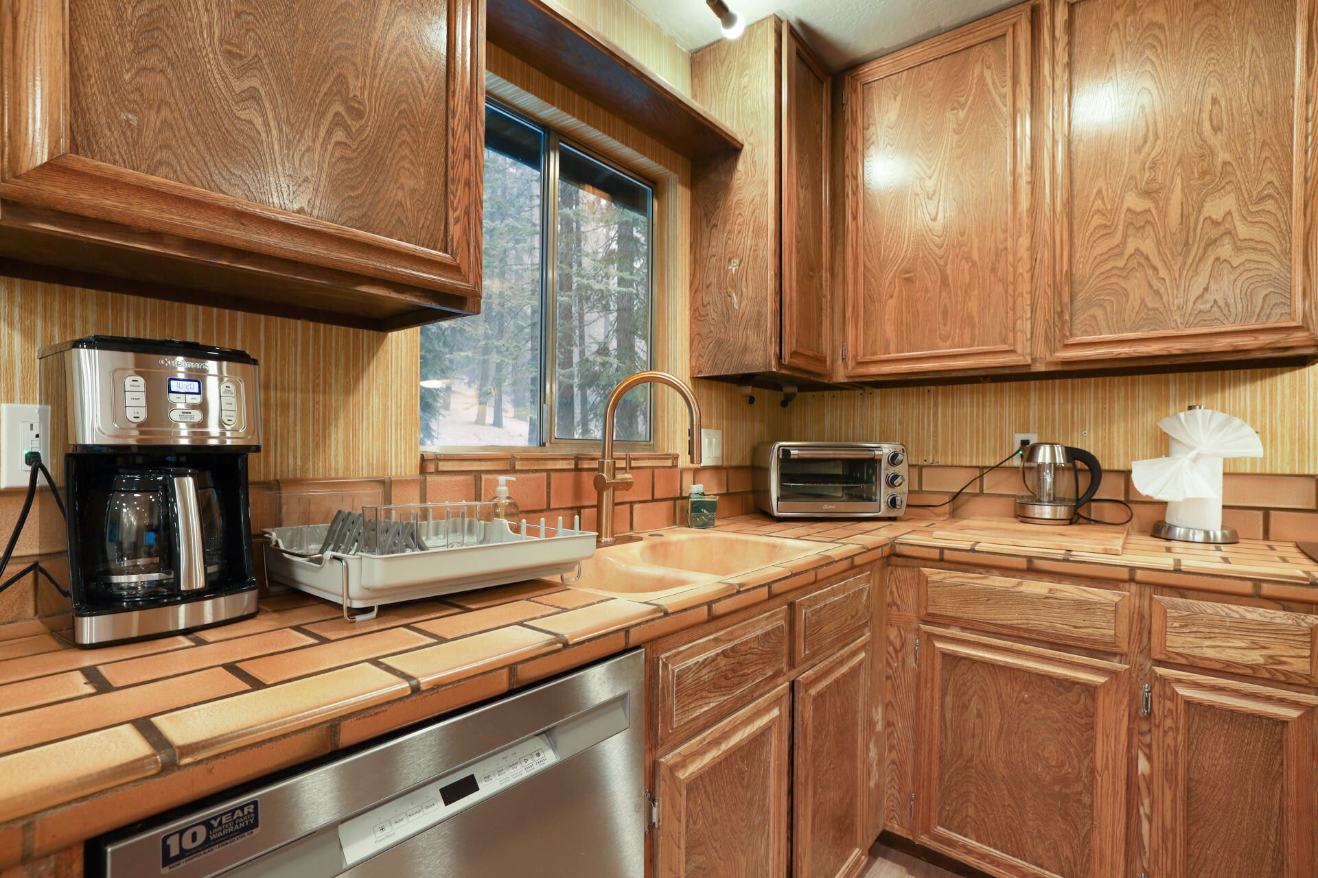 A kitchen with wooden cabinets, a coffee maker, a toaster, and a dishwasher.
