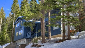 A multi-story building with a blue exterior, surrounded by tall pine trees and snow-covered ground. - Southern Pines Arcade Games & Foosball for Kids! (South Lake Tahoe)