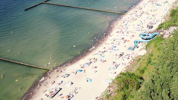 An aerial view of a beach with clear water, a sandy shore, and a blue water slide. - 1 bedroom beautiful apartment in Jaroslawiec (Jaroslawiec)