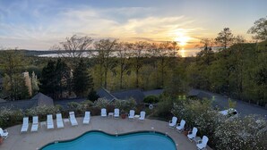 Ein Pool mit Liegestühlen, umgeben von Bäumen und Blick auf den Sonnenuntergang.