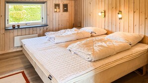 Ein Zimmer mit Holzwänden, einem Bett, einem Fenster und Wandleuchten.