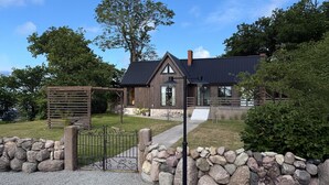 A modern house with a dark roof, a wooden fence, and a stone wall in front. - Pet friendly home in Löttorp with WiFi (Löttorp)