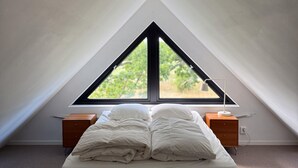 A bedroom with a bed, two nightstands, a lamp, and a window with a view of greenery. - Pet friendly home in Löttorp with WiFi (Löttorp)