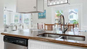 A modern kitchen with a built-in dishwasher, stainless steel sink, and a light fixture above the counter.