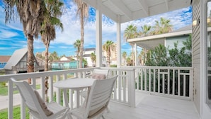 A covered outdoor area with a white table and two chairs, surrounded by a white railing.