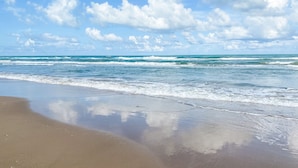 A beach with waves and a clear sky.