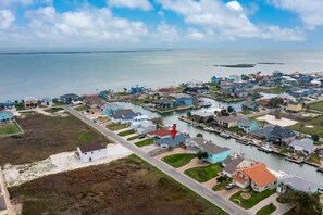 Vista aérea de una zona residencial costera con casas, un puerto deportivo y una gran masa de agua.
