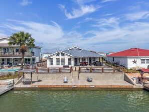 A waterfront property with a pool, outdoor seating, and a dock.