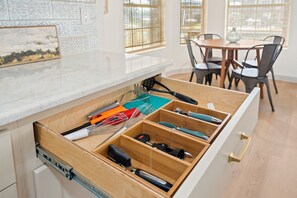 Une cuisine avec un organiseur en bois pour les tiroirs, contenant divers ustensiles.