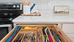 A kitchen drawer with utensils and a stove in the background. - NEWLY REMODELED - Rockport Waterfront Oasis (Rockport)
