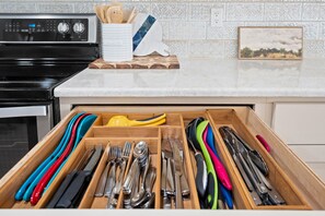 Un tiroir de cuisine contenant des ustensiles, avec une cuisinière en arrière-plan.