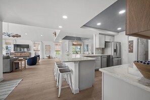 A modern kitchen with a central island, white cabinetry, and stainless steel appliances.