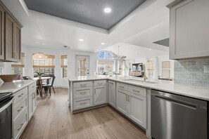 A modern kitchen with white cabinetry, stainless steel appliances, and a large island. - NEWLY REMODELED - Rockport Waterfront Oasis (Rockport)