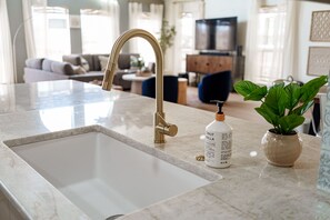 Una cocina moderna con encimera de mármol, grifo dorado y una planta en maceta.