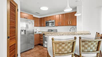 A modern kitchen with wooden cabinets, stainless steel appliances, and a granite countertop.