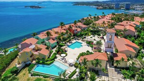 Un resort con varias edificaciones, una piscina y vista al océano.