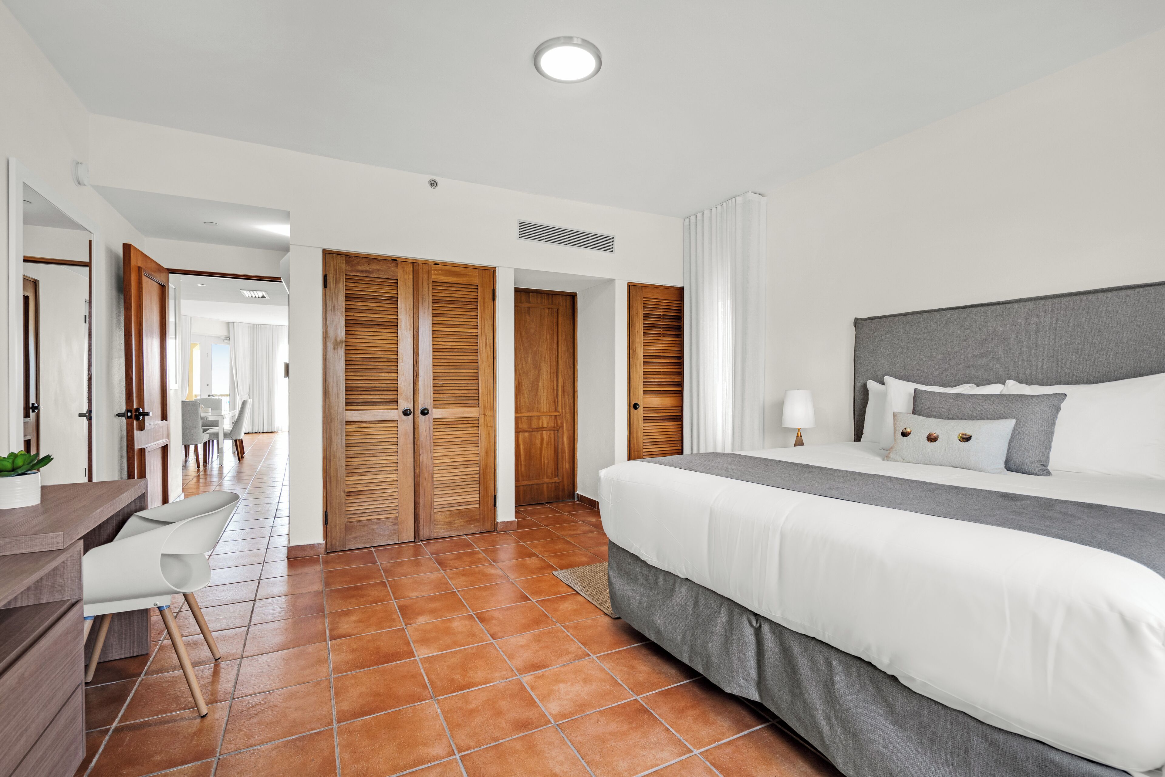 Una habitación de hotel moderna con una cama grande, un escritorio con silla y un baño con ducha.