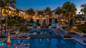 Un área de piscina en un resort con varias piscinas, sillas de descanso y palmeras.