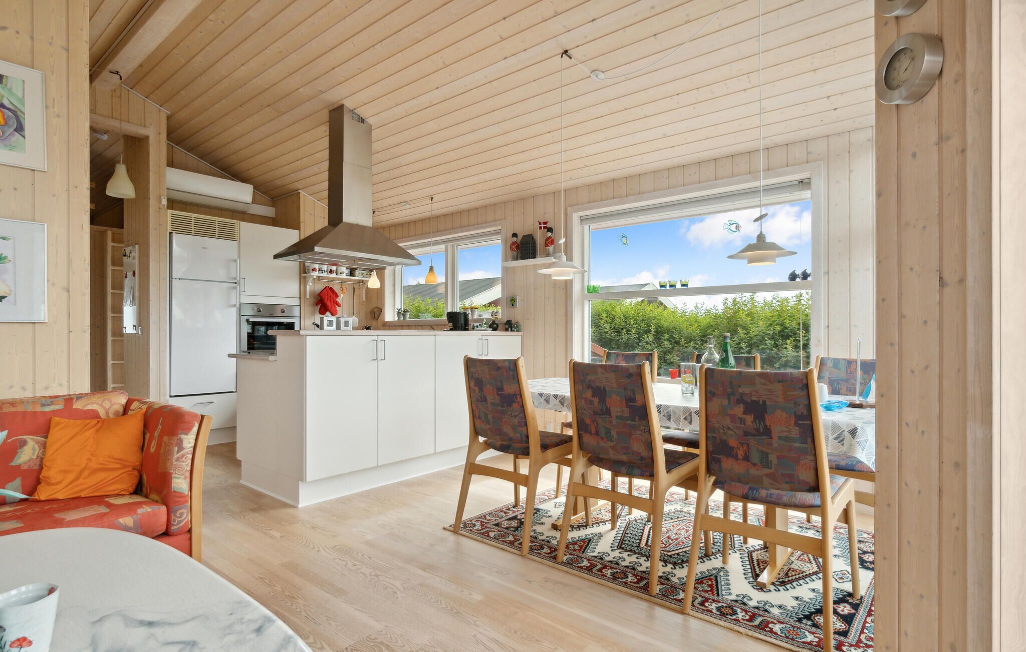 A modern kitchen with white cabinets, a built-in oven, and a large window overlooking a garden.