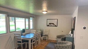 A compact living space with a dining area, a patterned sofa, and a framed picture on the wall. - Evans Corner-A Libby Original (Libby)