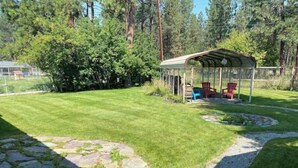 A covered outdoor seating area with chairs, a stone pathway, and a well-maintained lawn. - Evans Corner-A Libby Original (Libby)