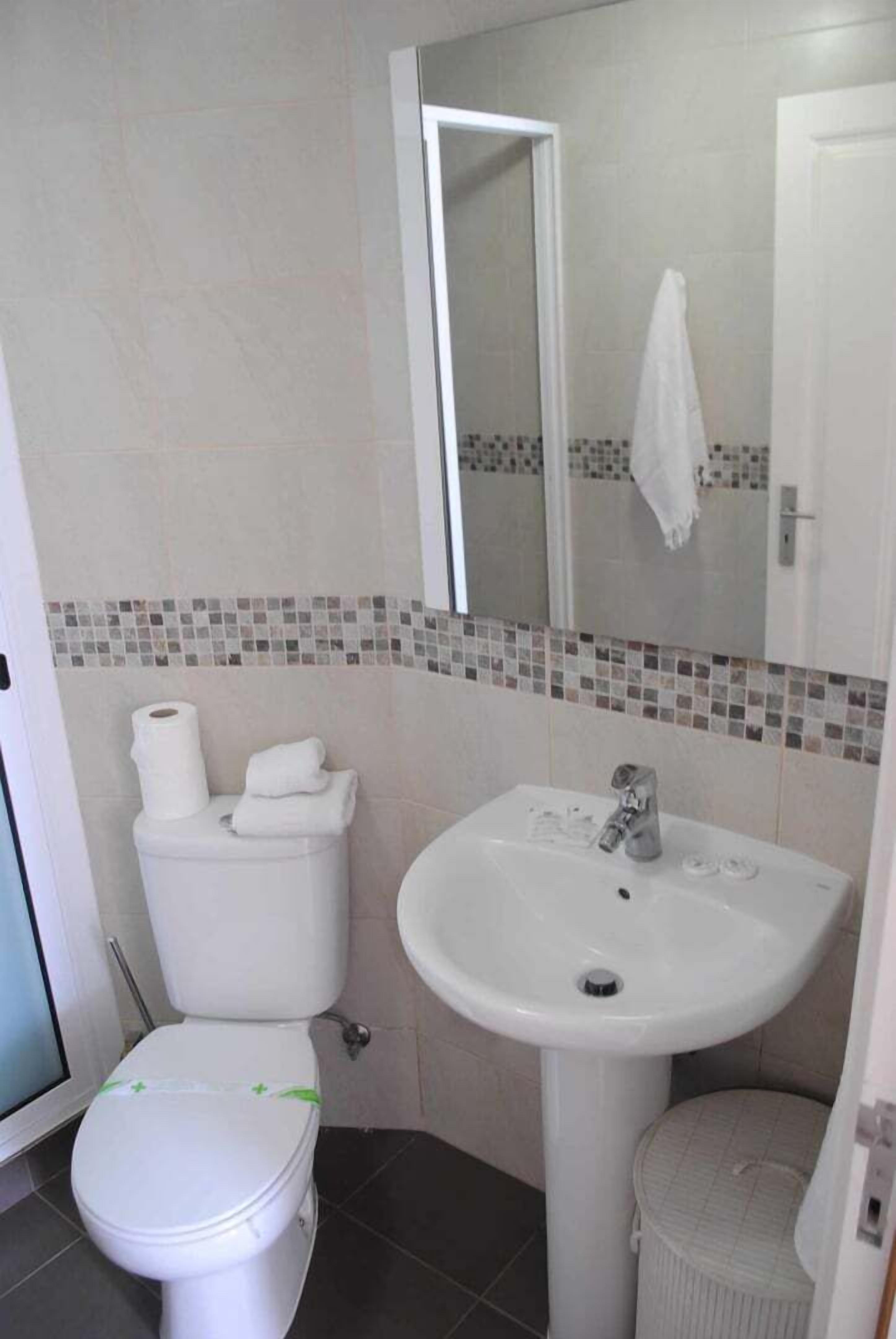 Ein Badezimmer mit Toilette, Waschbecken und Spiegel.