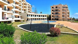 Um hotel com vários andares, piscina ao ar livre, área de recreação infantil e um jardim bem cuidado.