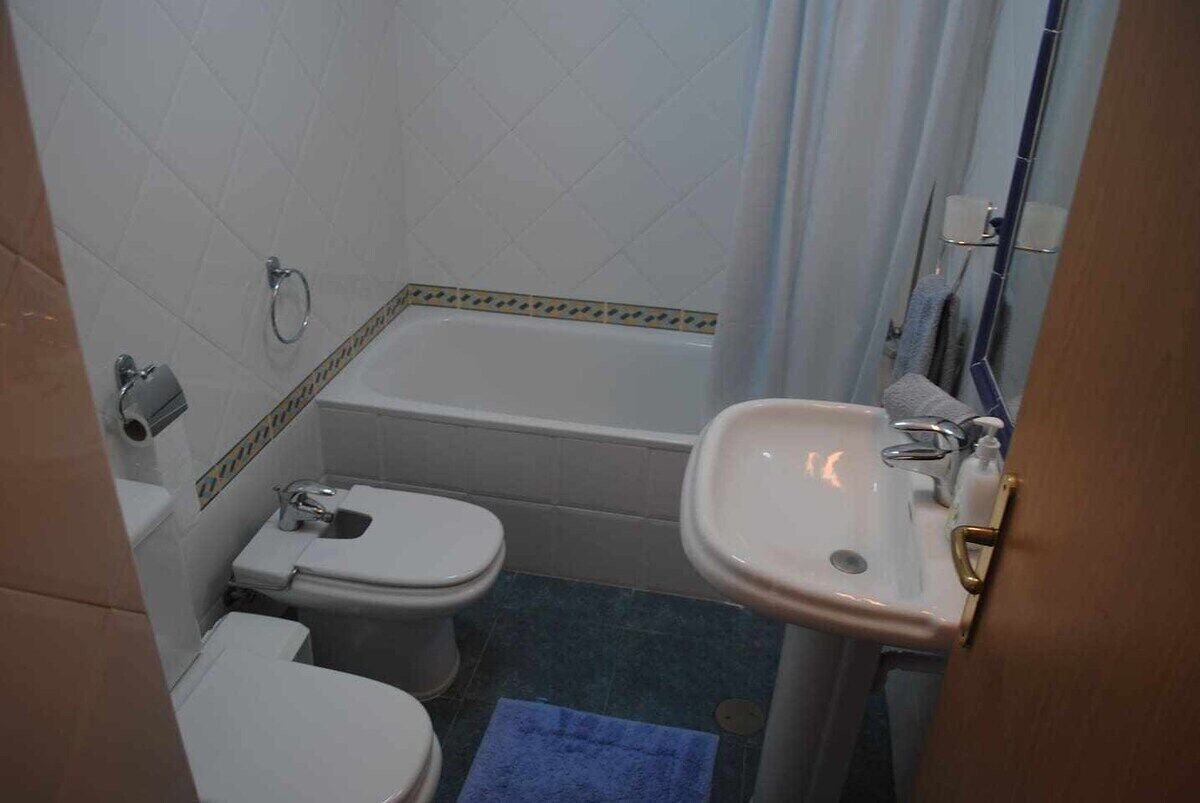 Een compacte badkamer met toilet, wastafel en bad.