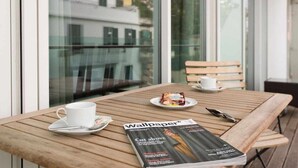 Une table en bois avec un magazine, une tasse et une assiette contenant de la nourriture.