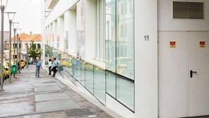Un bâtiment moderne doté d’une façade en verre, d’un espace extérieur couvert et d’une porte d’entrée bien visible.