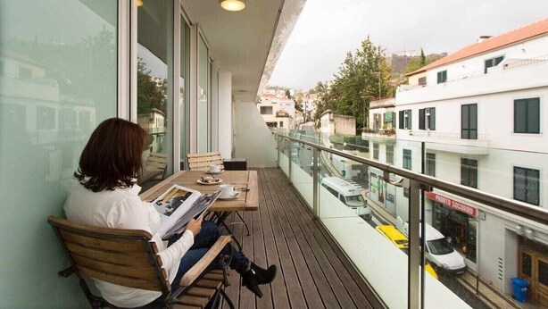 Un balcon donnant sur une rue et des immeubles.