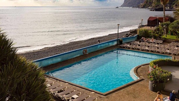 Ein Pool mit Blick auf den Ozean und einen Strand.