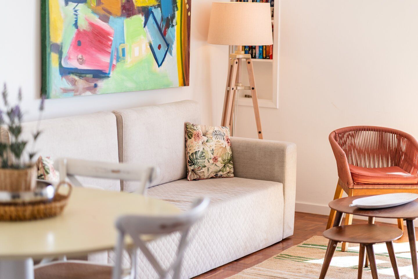 Un salon moderne comprenant un canapé, un fauteuil en osier, une table à manger et un lampadaire.