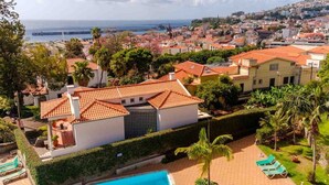 A residential area with a swimming pool, palm trees, and a view of the sea. - Varandas Funchal-Near center (Funchal)