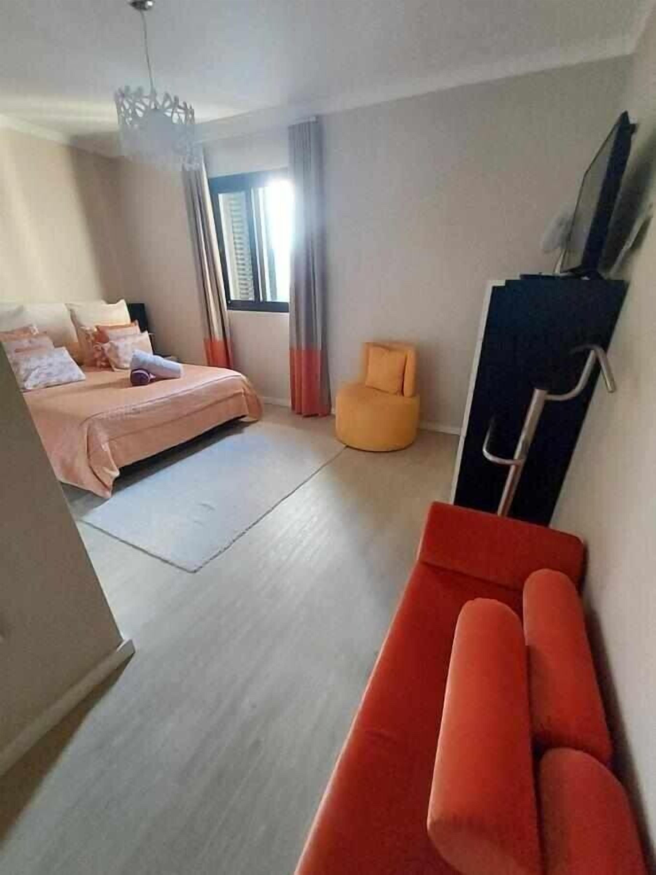 A bedroom with a bed, a chair, a desk, and a wardrobe.